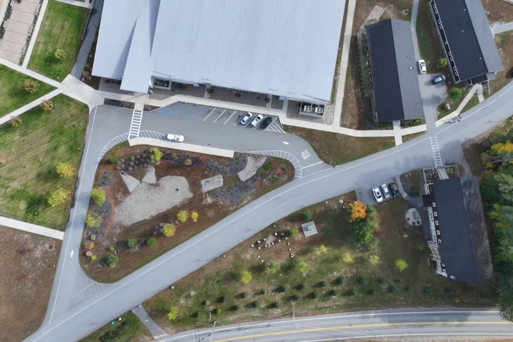 Aerial view of landscape architecture site design with curved hardscape, planted beds, parking area, and green spaces