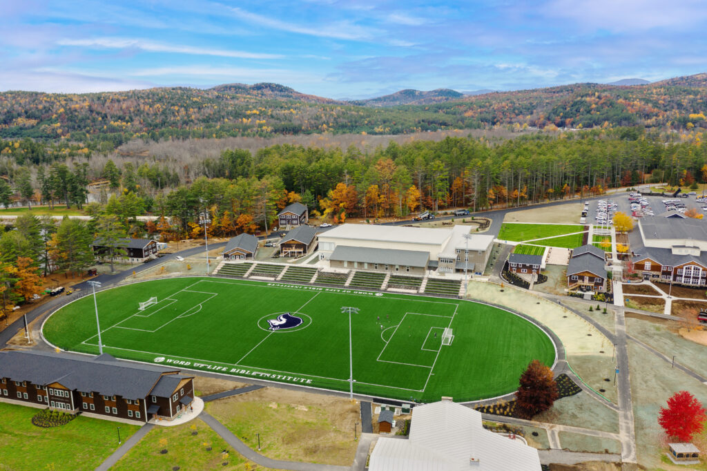 Aerial view of athletic field with manicured soccer pitch and surrounding campus buildings nestled in forested Northeast