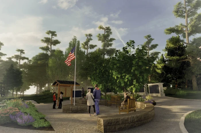 Public plaza with stone seating, native plantings, and flag pole surrounded by mature trees and woodland landscape design