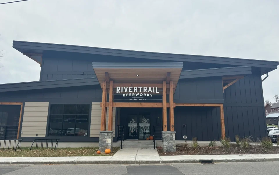 Modern commercial building with dark blue exterior, wood accents, and stone entry pillars in Saratoga Lake, NY
