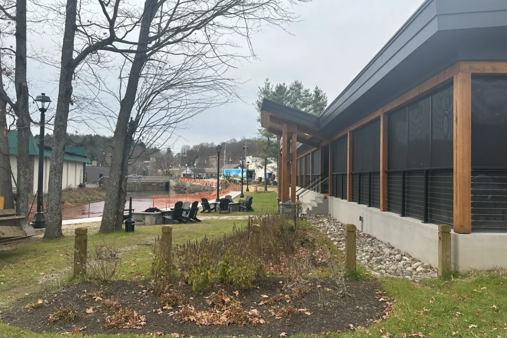 Modern waterfront site design with native plantings, wooden deck, and landscaped grounds overlooking riverside park.