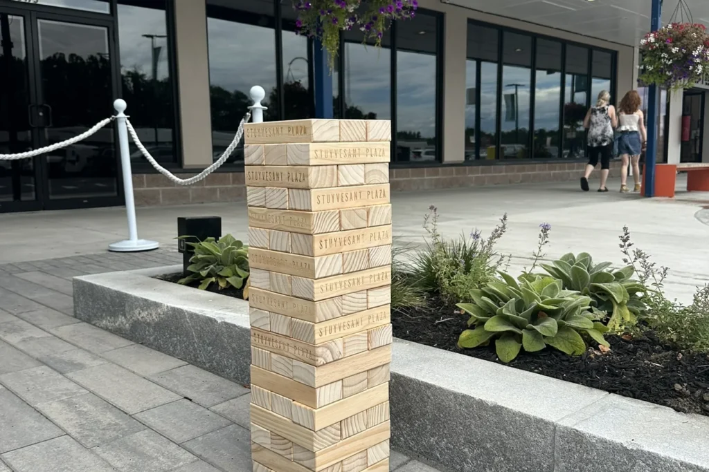 Stuyvesant Plaza outdoor seating area with wooden wayfinding tower, concrete planters with ornamental grasses and succulents