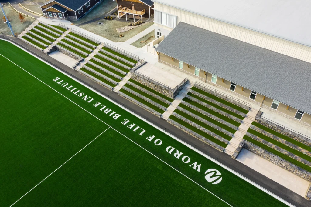 Aerial view of tiered green seating amphitheater with stone retaining walls and modern building adjacent to manicured